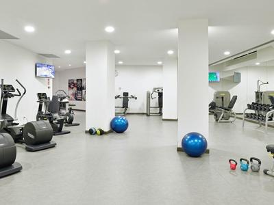 Moderner Fitnessraum mit verschiedenen Trainingsgeräten und Gymnastikbällen in hellen Räumen.