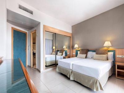 Helles Hotelzimmer mit zwei Betten, großem Spiegel und modernem Mobiliar.