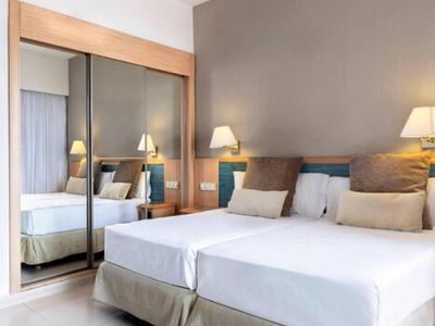 Modernes Hotelzimmer mit zwei Betten, grauer Wand und großem Spiegel mit Holzrahmen.
