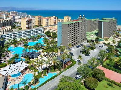 Velký hotelový resort s několika bazény, palmami a výhledem na moře.