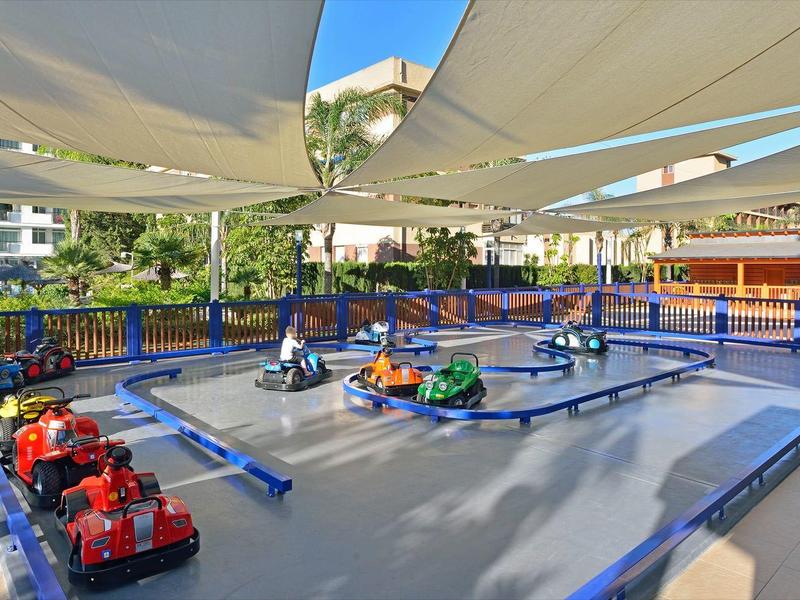 Elektrické motokáry na venkovní dráze se slunečními stínícími plachtami v hotelové oblasti.