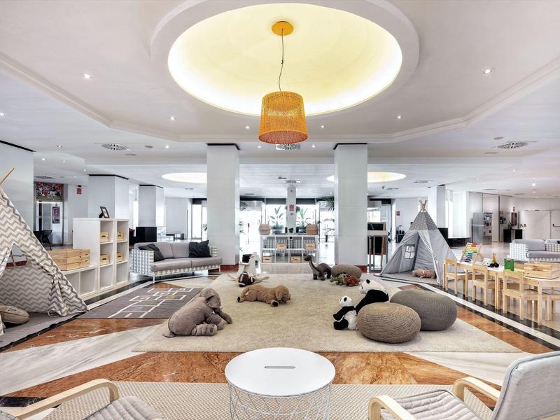 Prostorný, světlý vnitřní prostor s pohodlnými polštáři a dětskou hernou v hotelu.