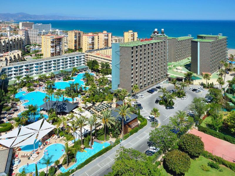 Velký hotelový resort s několika bazény, palmami a výhledem na moře.