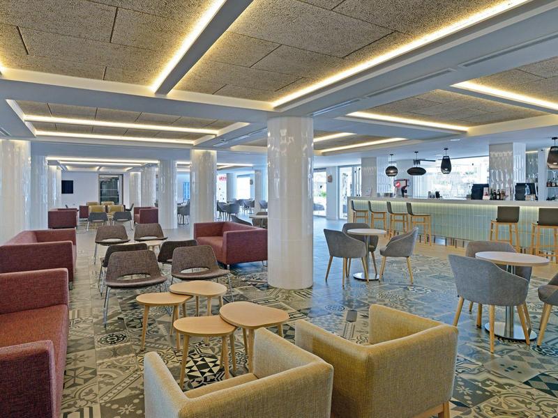 Moderner Lounge-Bereich mit Sofas, Sesseln, Tischen und Bar in hellem, offenem Raum.