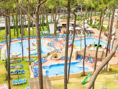 Venkovní hotelový bazén s několika propojenými bazény obklopenými lehátky a slunečníky.