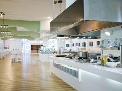 Helle moderne Restaurantküche mit weißer Einrichtung und Holzboden.