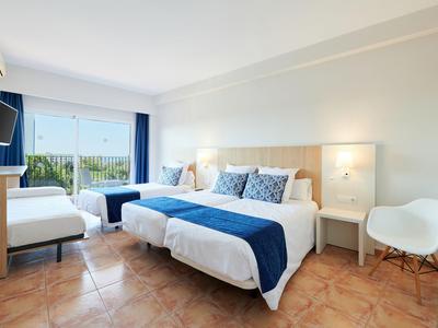 Helles Hotelzimmer mit Doppelbett, blauen Akzenten und Balkon mit Blick auf die Natur.