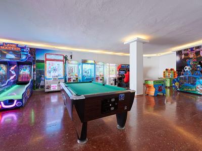 Ein heller Spielraum mit Billardtisch und verschiedenen Arcade-Spielen mit bunter Beleuchtung.