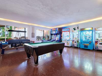 Ein heller Spielraum mit einem Billardtisch, Airhockey und mehreren Spielautomaten in einem Hotel.