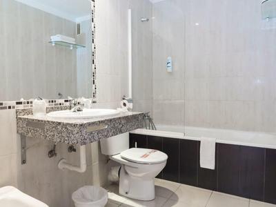 Moderní koupelna se umyvadlem, zrcadlem, toaletou a vanou s ručníkem.