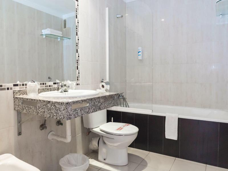 Moderní koupelna se umyvadlem, zrcadlem, toaletou a vanou s ručníkem.