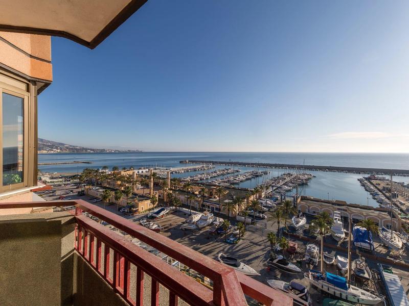 Vista dal balcone dell'hotel sul porto e sul mare con cielo sereno.