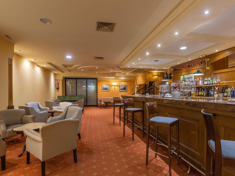 Accogliente bar dell'hotel con poltrone in pelle e un lungo bancone in legno.