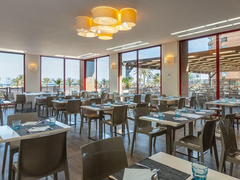 Sala da pranzo moderna con tavoli in legno e grandi finestre in un hotel.