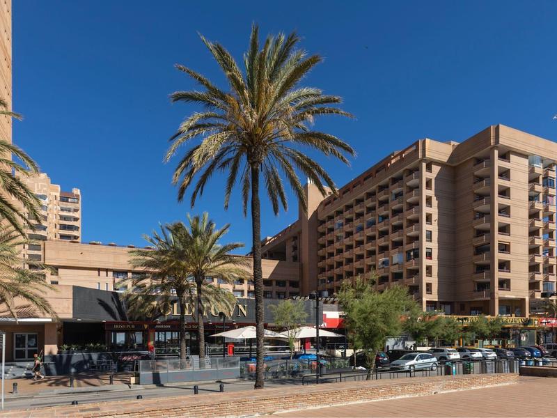 Grande edificio dell'hotel con palme sotto un cielo azzurro e soleggiato.