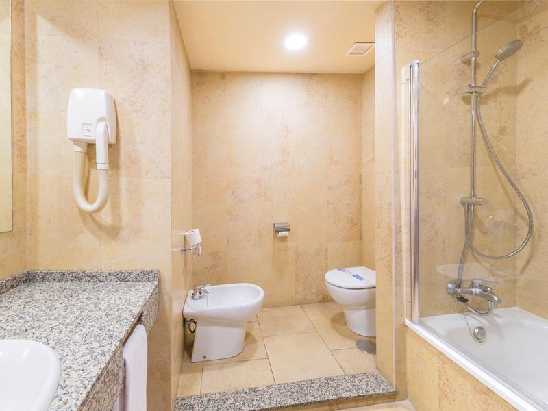 Bagno luminoso con vasca, bidet, WC e piano in marmo.