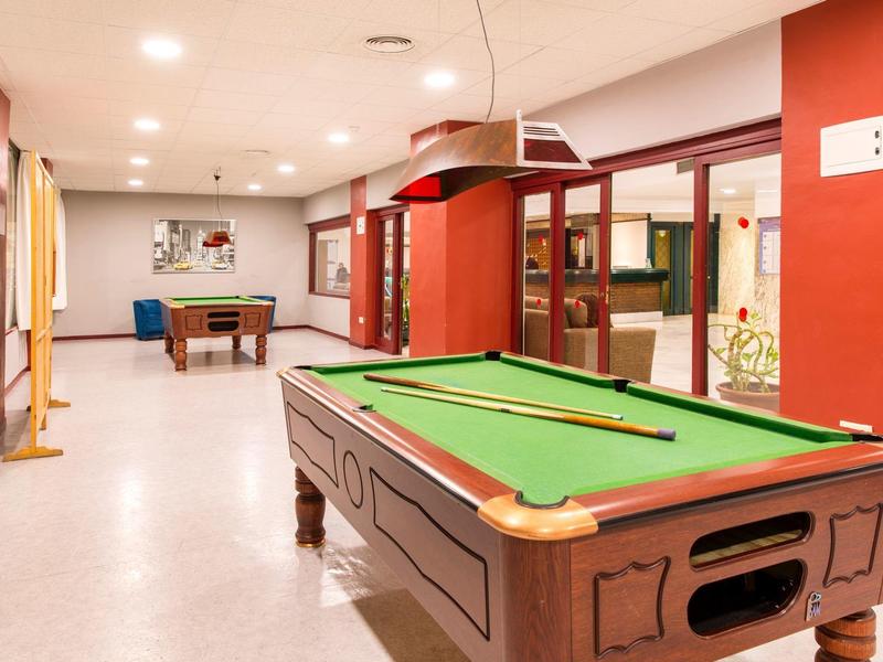 Una stanza ben illuminata con un tavolo da biliardo verde e altre strutture ricreative.