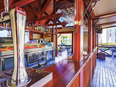 Open bar with wooden paneling and seating area overlooking terrace and sea.