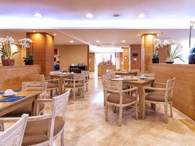 Bright, modern hotel restaurant with wooden furniture and orchids on tables.