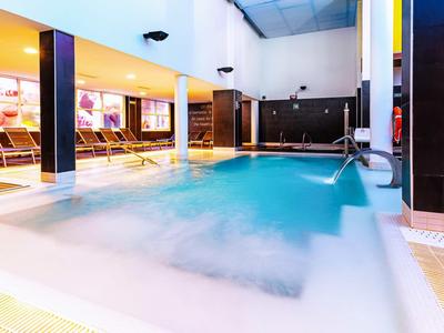 Indoor pool with water fountains and comfortable loungers in a modern hotel
