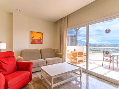 Bright living room with red armchair, gray sofa, and access to a terrace overlooking the sea.