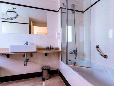 Modern bathroom with sink, bathtub, and glass shower enclosure.