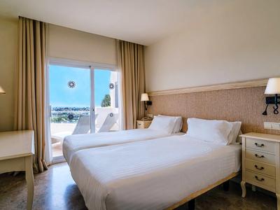 Cozy hotel room with double bed and view of terrace and sea.