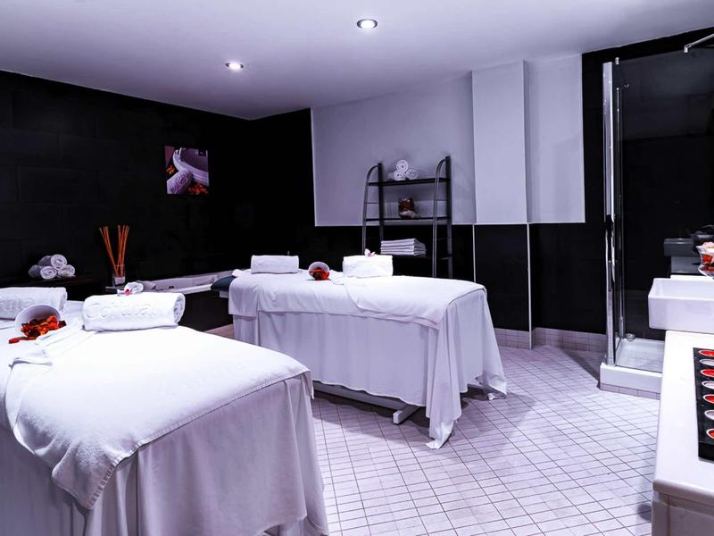 Modern spa with two massage tables, white towels, and a relaxing atmosphere.