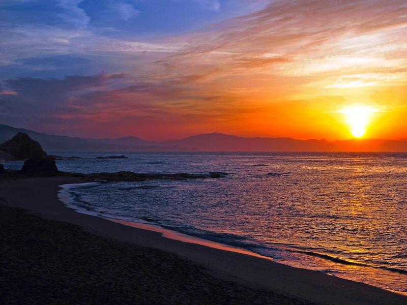 Beach at sunset with orange sky and calm sea