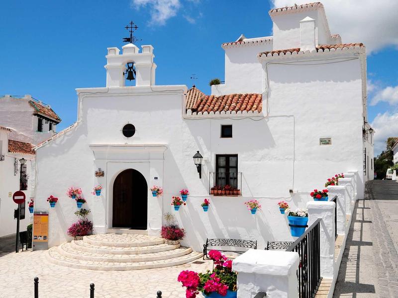 White building with stairs and colorful flower decorations under clear sky.