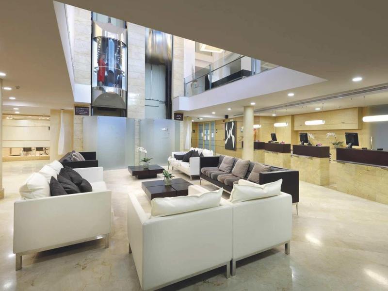 Modern hotel lobby with comfortable white sofas and elevators in the background.