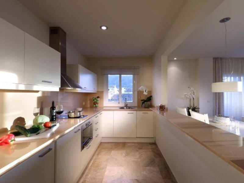 Modern kitchen with wooden countertops and white cabinets in a bright hotel room.