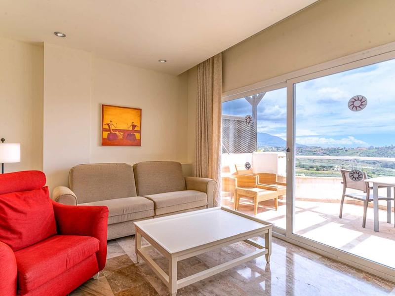 Bright living room with red armchair, gray sofa, and access to a terrace overlooking the sea.