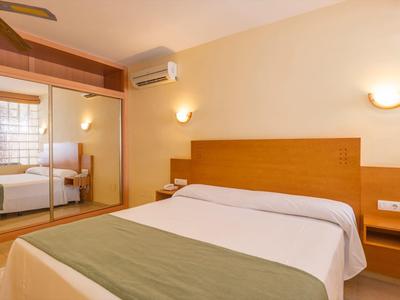 Cozy hotel room with double bed, nightstands, and large mirrored wardrobe.