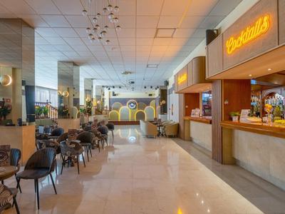 Modern hotel lobby with seating area, bar, and decorative illuminated wall design.