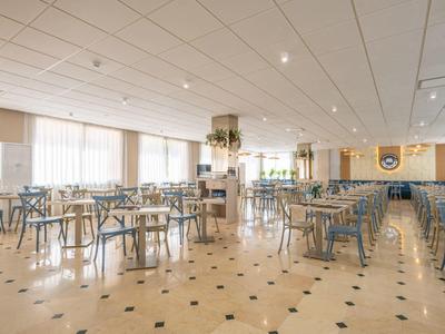 Bright, spacious restaurant with many tables and chairs, modern design, and large windows.