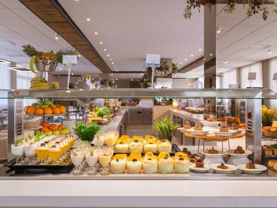 Buffet with various desserts and fruits in a bright restaurant.