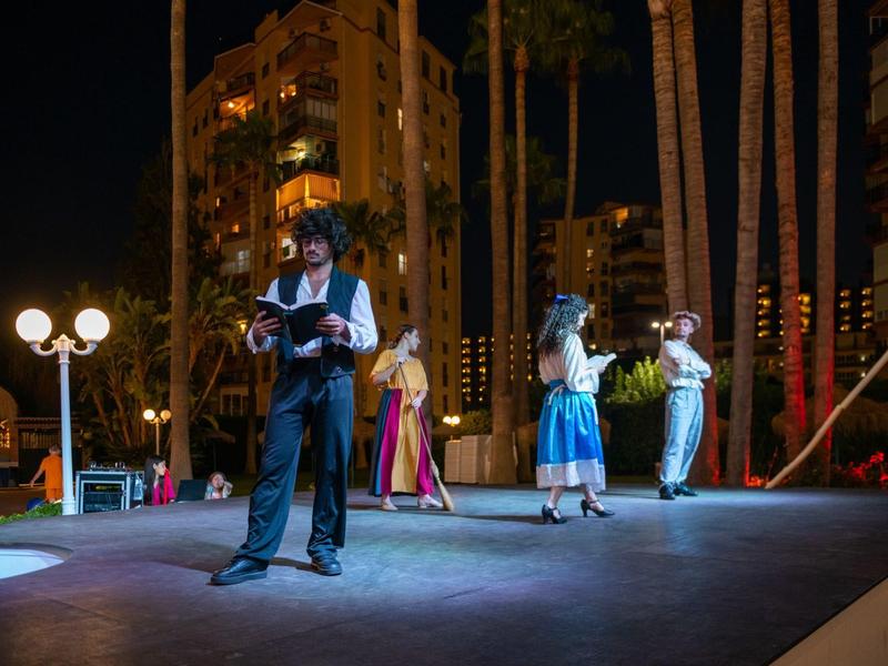 Stage performance with four actors on a lit outdoor stage at night