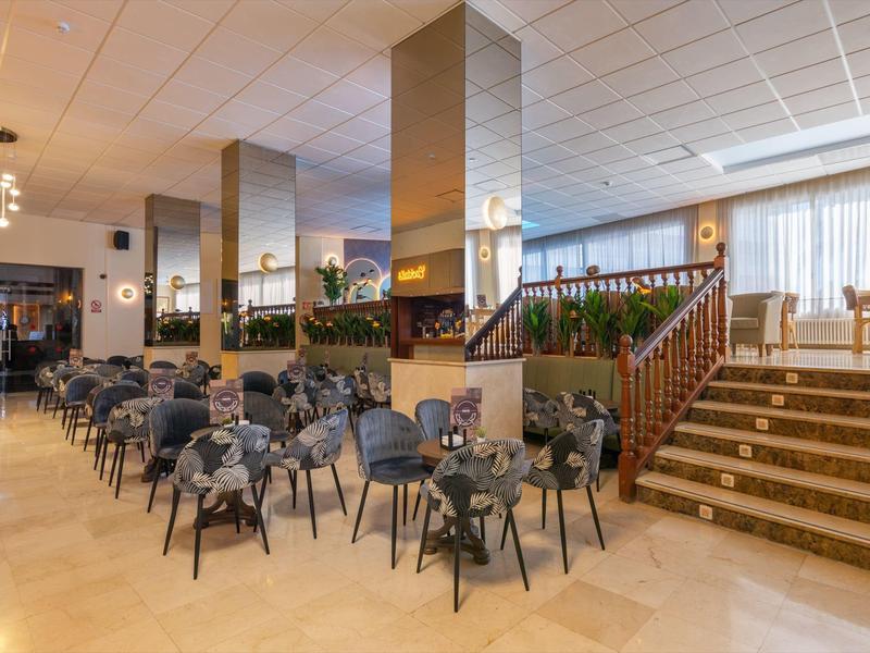 Modern hotel lounge with cozy seating areas and large staircase to upper floor.