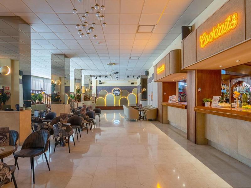 Modern hotel lobby with seating area, bar, and decorative illuminated wall design.