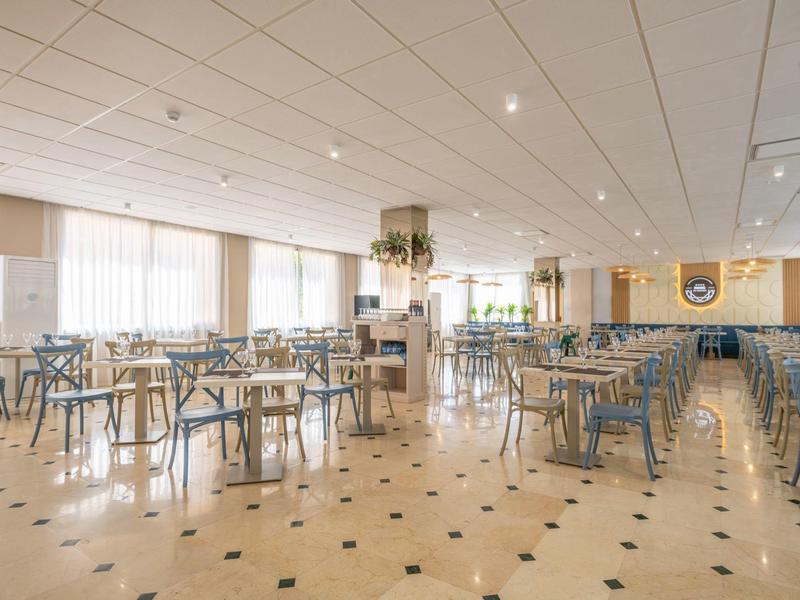 Bright, spacious restaurant with many tables and chairs, modern design, and large windows.