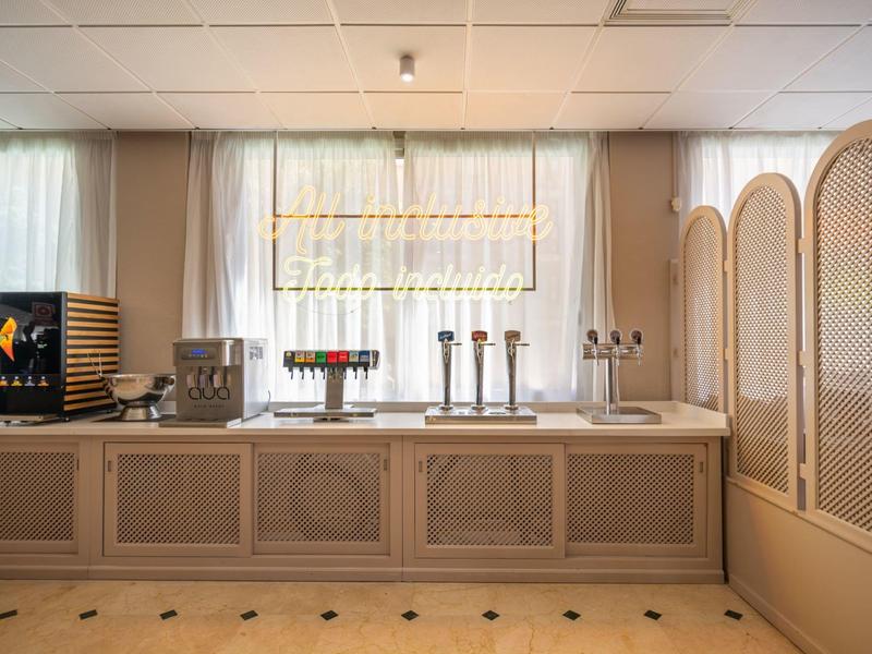 Elegant hotel bar with wooden paneling, taps, and indirect lighting behind the counter.