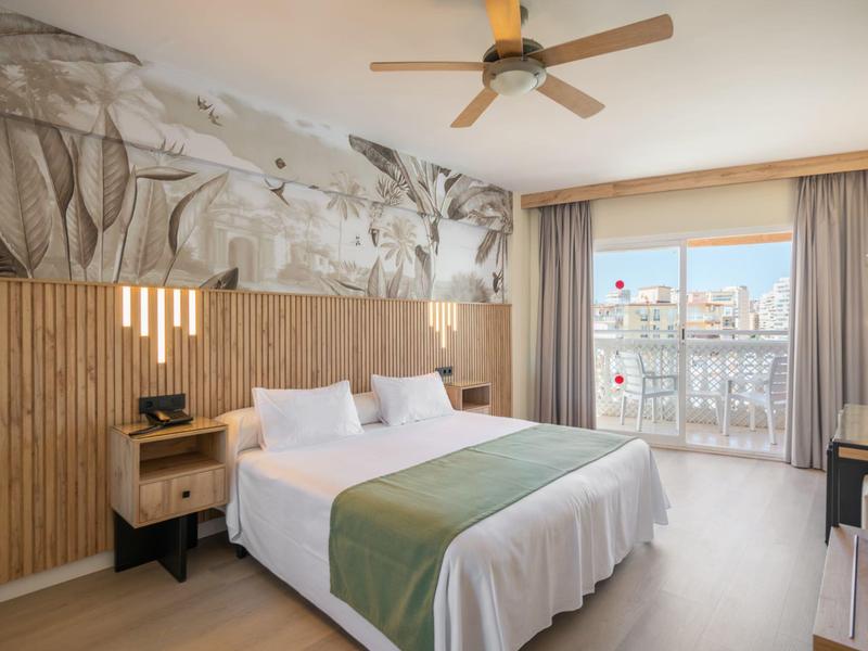 Modern hotel room with double bed, large window, and atmospheric wall art.