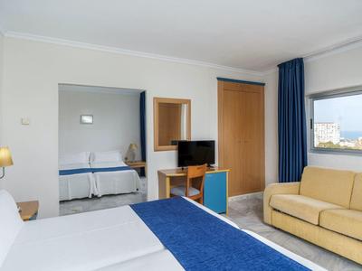 Camera d'hotel con due letti, un divano, TV e vista dalla finestra.