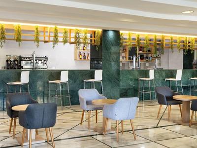 Moderne Hotelbar mit stilvollen Stühlen und hellem Marmorboden.
