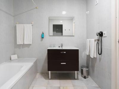Modernes Badezimmer mit weißem Waschbecken, braunem Waschtischunterschrank und Badewanne.
