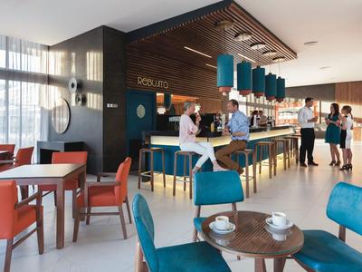 Interno moderno di un bar con sedie colorate e personale al servizio.