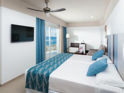 Camera d'hotel moderna con letto matrimoniale, TV a parete e balcone con vista.