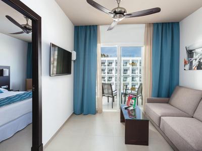 Camera d'hotel moderna con divano, letto, TV e balcone con vista sull'hotel.