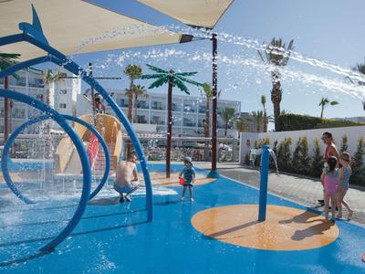 Area giochi d'acqua colorata con spruzzi in una località turistica.